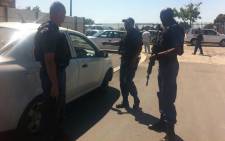 Armed Manenberg police officers are stationed near the house where a woman and her son were shot on 14 October 2014. Picture: Carmel Loggenberg/EWN.