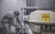 A morgue attendant at the Johannesburg branch of the South African funeral and burial services company Avbob checks the condition of a protective wrapping inside a refrigerated container where bodies of patients deceased with COVID-19 related illnesses are kept isolated ahead of their burials on 22 January 2021. Picture: AFP