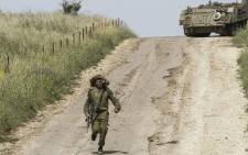 FILE: An Israeli soldier runs to direct a M113 armoured personnel vehicle near the Syrian border in the Israel-annexed Golan Heights on 10 May 2018. Picture: AFP