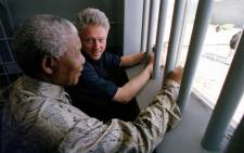 Former US President Bill Clinton and South African President Nelson Mandela look out the jail cell window 27 March where Mandela spent 18 of his 27 years as a political prisioner on Robben Island. Picture: AFP.