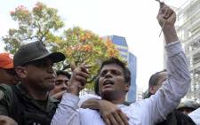 This file photo taken on February 18, 2014 shows Leopoldo Lopez (R), an ardent opponent of Venezuela's socialist government facing an arrest warrant, being escorted by the National Guard after turning himself in, during a demonstration in Caracas on February 18, 2014. Juan BARRETO / AFP