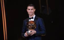This handout photo released on 7 December 2017 by L'Equipe shows Portugese player Cristiano Ronaldo posing with the Ballon d'Or France Football trophy in Paris. Picture: AFP.