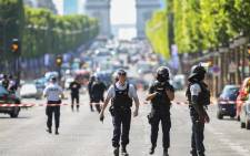 FILE: Police officers and anti-riot police officers patrol the Champs-Elysees Avenue on 19 June 2017 in Paris after a car crashed into a police van before bursting into flames, with the driver being armed, probe sources said. Picture: AFP.