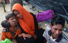 Rohingya refugees sit next to the body of their relative Anwara Begum, who died when their boat capsize during their Naf river crossing, in the Bangladeshi city of Teknaf on 14 September 2017. Picture AFP