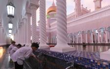 In this picture taken on 1 April 2019 children perform ablution before praying at the Sultan Omar Ali Saifuddien mosque in Bandar Seri Begawan in Brunei. Picture: AFP.
