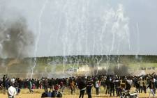 Palestinian protesters run for cover from tear gas fired by Israeli security forces during clashes following a demonstration commemorating Land Day, near the border with Israel, east of Gaza City, on 30 March 2018. Picture: AFP.