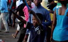 A young boy holding metal rods as weapons taunts the police during a violent service delivery protest. Picture: Sebabatso Mosamo/EWN.