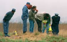 FILE: Members of the South African police force continue their search of a Boksburg field, east of Johannesburg, in September 1995, where the bodies of ten murder women victims were found. Picture: AFP.