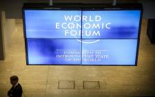 A delegate at the World Economic Forum 2015 stand underneath one of the forum's monitors. Picture: Thomas Holder/EWN