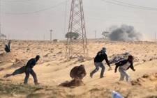 Libyan rebels run to cover as a tank shell of government forces explodes nearby on March 24, 2011. Picture: AFP