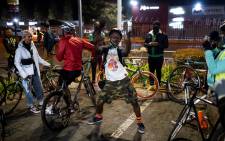 A member of the Biking Bandits dances while they take a break during the "Homies Night Ride" in Soweto on June 24, 2021. The Biking Bandits, a Soweto-based cycling crew, hosted a "Homies Night Ride." This is an evening cycling route through the streets of Soweto. Not only is it good fun and exercise, but it is also "a political statement," according to co-founder Tiyiselani Mashele, as it is a way to create visibility of black people on bicycles, reclaiming the streets. Picture: AFP.