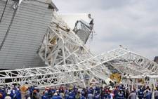 Workers examine the damage after a crane fell across part of the metallic structure at the Itaquerao stadium under construction in Sao Paulo. Picture: AFP.