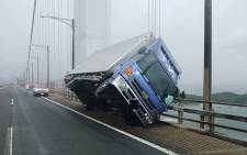 This handout photo released by the Kagawa Prefectural Police on 4 September 2018 and received via Jiji Press shows a truck sitting at an angle after being blown over by strong winds caused by Typhoon Jebi on the Seto Ohashi bridge in Sakade, Kagawa prefecture on Japan's Shikoku island. Picture: AFP