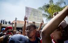A University of Pretoria student holds up a placard during protests on the institution’s Hatfield campus over possible university fee hikes for the 2017 academic year. Picture: Reinart Toerien/EWN.