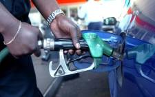 A petrol station attendant fills up a car tank. AFP