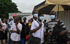 People wear protective masks as they wait at a bus stop outside Treichville university hospital in Abidjan, Ivory Coast, on 11 March 2020, where the first Ivorian case of new coronavirus was confirmed. Picture: AFP.
