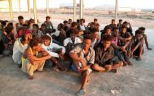 Rescued migrants sit on the coast of Khoms, some 100 kilometres (60 miles) from the Libyan capital Tripoli, on 26 July 2019. Picture: AFP