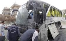 Syrian forensics examine a damaged bus at the scene of a bombing following twin attacks targeting Shiite pilgrims in Damascus' Old City on March 11, 2017. Picture: AFP.