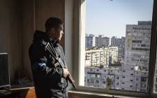 A police officer looks through the window of a damaged flat in a residential building hit by the debris from a downed rocket in Kyiv on 17 March 2022. 