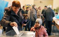 A woman casts her vote while holding her dog at a polling station on March 16, 2014 in Simferopol. Polls opened in Crimea on March 16 for a unique referendum on breaking away from Ukraine and join Russia that has precipitated a Cold War-style security crisis on Europe's eastern frontier. Picture: AFP.