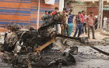 Iraqis look at the remains of a car bomb that detonated in the Kamaliya area of eastern Baghdad on 20 May 2013. Picture: AFP