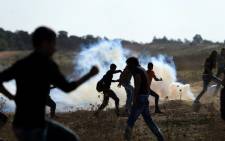 Palestinian protesters run for cover from teargas shot by Israeli soldiers during clashes near the border fence between Israel and the central Gaza Strip east of Bureij on 16 October 2015. Picture: AFP 