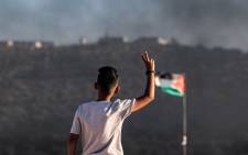 (FILES) In this file photo taken on July 6, 2021, a Palestinian youth flashes the victory sign while standing near a flying Palestinian flag in the town of Beita, near the occupied West Bank city of Nablus, opposite the newly-established Israeli wildcat settler outpost of Eviatar. Using laser pointers and noisy horns to torment Jewish settlers across the valley, Palestinians in Beita have set themselves apart from others demonstrating against Israel's occupation of the West Bank.
JAAFAR ASHTIYEH / AFP