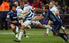 Stormers players Juan De Jongh (C) fends off the tackle of Auckland Blues player Chris Noakes.  Picture: AFP.