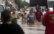 Residents and tourists wade through a flooded street in Acapulco, Guerrero state, Mexico, after heavy rains hit the area on 16 September 2013. Picture: AFP