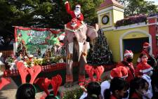 An elephant from the Ayutthaya Elephant Palace, dressed in a Santa Claus costume and wearing a face mask, is greeted by students during an event to hand out face masks outside the Jirasat Wittaya School in the central Thai province of Ayutthaya on December 23, 2020. Picture: AFP.