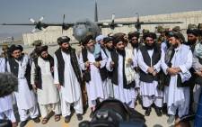 Taliban spokesperson Zabihullah Mujahid (C, with shawl) speaks to the media at the airport in Kabul on 31 August 2021. The Taliban joyously fired guns into the air and offered words of reconciliation as they celebrated defeating the United States and returning to power after two decades of war that devastated Afghanistan. Picture: Wakil Kohsar/AFP