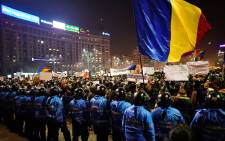 Romanian riot police stand guard as people demonstrate against controversial decrees to pardon corrupt politicians and decriminalize other offenses in front of the government headquarters in Bucharest. Picture: AFP.