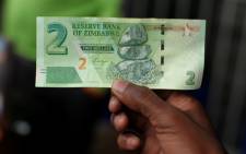 FILE: A man holds a bond note released by the Reserve Bank Of Zimbabwe in Harare central business centre. Picture: AFP.