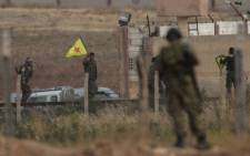 Kurdish People's Protection Units (YPG) fighters hold their movement's flag while a Turkish soldier looks at them near the Akcakale crossing gate in Sanliurfa province in June 2015. Picture: AFP.