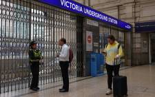 A police officer talks to a commuter at the shuttered entrance to Victoria underground tube station in London on 6 June 2022, during a 24-hour strike by nearly 4,000 London Underground station staff. Picture: Hollie Adams/AFP