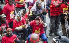 Striking workers clad in red wave sticks as they demonstrate on the first day of a nationwide strike called by Numsa to demand a pay raise of up to 12 percent and better working conditions, in Johannesburg Central Business District on 1 July, 2014. Picture: AFP.
