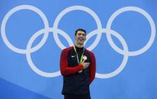 USA’s Michael Phelps laughs on the podium with his gold medal. Picture: AFP.