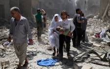 FILE: A Syrian family walks amid the rubble of destroyed buildings following a reported airstrike on 28 April 2016 in the Bustan al-Qasr rebel-held district of the northern Syrian city of Aleppo. Picture: AFP.