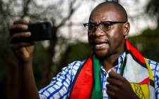 This file photo taken on 19 May 2016 shows Zimbabwean cleric Evan Mawarire, wrapped in the Zimbabwean national flag, recording an installment of his #ThisFlag video series. Picture: AFP.
