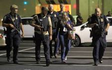 Dallas police officers escort a woman near the scene where Dallas police officers were shot on 7 July 2016. Picture: AFP. 