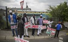 FILE: Unemployed builders, tilers and plumbers hold signs seeking jobs on the side of the road in Johannesburg. Picture: AFP