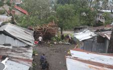 People stand by damaged houses and fallen trees on April 25, 2019 in Moroni after tropical storm Kenneth hit Comoros before heading to recently cyclone-ravaged Mozambique. Picture: AFP