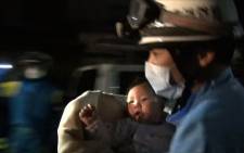 This handout image taken from video footage released by the Kumamoto Prefectural Police on April 15, 2016 shows a rescue worker carrying an eight-month-old baby girl after she was pulled from the rubble following an earthquake in Mashiki, Kumamoto Prefecture. Rescuers were scrambling to find survivors on April 15 after a powerful earthquake in southern Japan that left at least nine people dead and hundreds injured, sparking fires and buckling roads. Picture: AFP/ STR / Kumamoto Prefectural Police