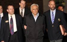 IMF head Dominique Strauss-Kahn (C) is taken out of a police station in New York on May 15, 2011 after he was charged with attempting to rape. Picture: AFP.