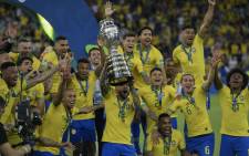Brazil's Dani Alves (C) raises the trophy as he celebrates with teammates after winning the Copa America after defeating Peru in the final match of the football tournament at Maracana Stadium in Rio de Janeiro, Brazil, on 7 July 2019. Picture: AFP
