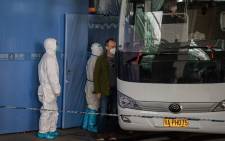 A member of the World Health Organization (WHO) team investigating the origins of the COVID-19 pandemic boards a bus following their arrival at a cordoned-off section in the international arrivals area at the airport in Wuhan on 14 January 2021. Picture: NICOLAS ASFOURI/AFP