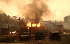 FILE: Burned out cars sit next to a building on fire in a fire-ravaged neighbourhood on 9 October 2017 in Santa Rosa, California. Picture: AFP.