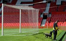 A sniffer dog searches behind one of the goals at Old Trafford stadium in Manchester, north west England, on May 15, 2016, after the English Premier League football match between Manchester United and Bournemouth was abandoned. Police ordered Manchester United to abandon their final Premier League game of the season against Bournemouth on Sunday after a suspicious package was discovered at Old Trafford. Picture: AFP.