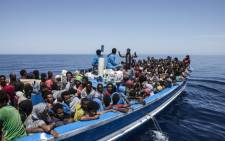 FILE: A handout picture taken on 3 May, 2015 released by the MOAS (Migrant Offshore Aid Station) shows migrants aboard a wooden boat on the Mediterranean sea. Picture: AFP.