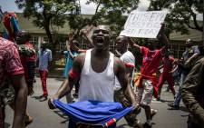 A Congolese protester holds a book of the DRC's constitution in defiance against DRC President Joseph Kabila at a protest at the country's embassy in Pretoria on 20 December 2016 in Pretoria. Picture: AFP.